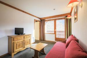a living room with a red couch and a tv at Résidence Les Valmonts - maeva Home - Appartement 3 Pièces 6 Personnes - Confort MAE-2689 in Saint-Martin-de-Belleville