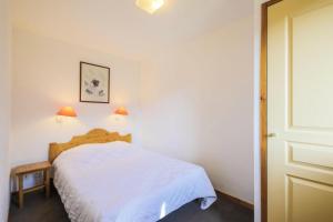 1 dormitorio con 1 cama con colcha blanca en Résidence Les Valmonts - maeva Home - Appartement 3 Pièces 6 Personnes - Co 89 en Saint-Martin-de-Belleville