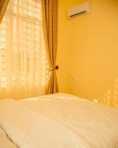 Cama blanca en habitación con ventana en Nellly's Rest House en Dar es Salaam