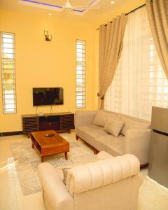 a living room with a couch and a tv at Nellly's Rest House in Dar es Salaam