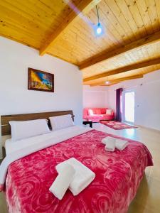 a bedroom with a large bed with a red blanket at Lahuta e Vjeter Agroturizem in Laç