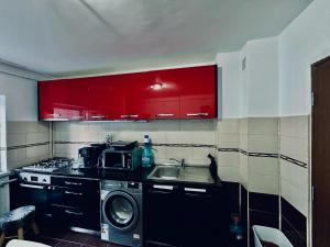 a kitchen with red cabinets and a washing machine at Apartament ASK HOME in Slănic-Moldova +8 photos
