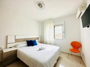 ein weißes Schlafzimmer mit einem Bett und einem orangenen Stuhl in der Unterkunft BOOK SOLEMIO MIAMI PLAYA - ONLY FAMILIES in Miami Platja
