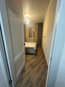 um corredor com um quarto com uma cama e uma porta aberta em Апартаменты в ЖК "AURUS" em Almaty