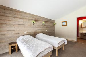 two beds in a room with a wooden wall at Résidence Le Christiana - maeva Home - Appartement 3 Pièces 7 Personnes - Sélection MAE-4070 in Saint-Bon-Tarentaise
