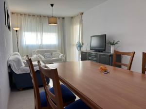 un salon avec une table en bois et une télévision dans l'établissement Garden Teatinos, apartamento con piscina y AC, à Malaga