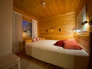 ein Schlafzimmer mit einem Bett in einem Holzzimmer in der Unterkunft Alppiruusu B in Syöte