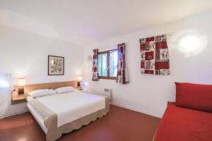 - une chambre avec un lit et un canapé rouge dans l'établissement Résidence les Chalets D'aurouze - maeva Home - Appartement 2 Pièces 5 Perso 67, à Saint-Étienne-en-Dévoluy