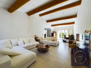 Elle comprend un salon doté d'un mobilier blanc et de plafonds en bois. dans l'établissement Maison la Garrigue en Provence, à Maillane