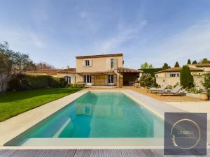 une villa avec une piscine en face d'une maison dans l'établissement Maison la Garrigue en Provence, à Maillane