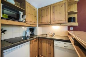 a kitchen with wooden cabinets and a sink and a microwave at Quartier La Forêt - maeva Home - Appartement 2 Pièces 6 Personnes - Sélect 74 in Valmorel