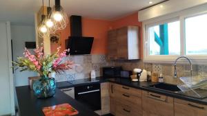 a kitchen with a vase of flowers on a counter at Le gîte de la Racine "La Verte Vallée" in Raon-aux-Bois +1 photo