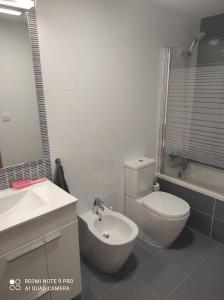 La salle de bains blanche est pourvue de toilettes et d'un lavabo. dans l'établissement Apartamento nuevo en playa de Piles. Costa Blanca, à Piles