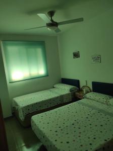 Cette chambre comprend deux lits et un ventilateur de plafond. dans l'établissement Apartamento nuevo en playa de Piles. Costa Blanca, à Piles