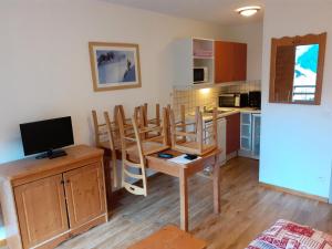 a kitchen with chairs and a table with a television at Résidence Le Hameau des Ecrins - maeva Home - Appartement 2 Pièces 6 Person 59 in Puy-Saint-Vincent