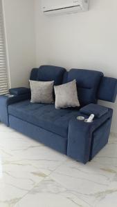 um sofá azul com duas almofadas numa sala de estar em Apartamento Flandes em Flandes