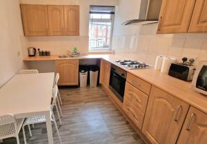 a kitchen with wooden cabinets and a table and a stove at Comfy Apartment - Nottingham Centre - Free Parking in Nottingham