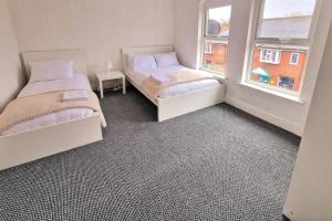 two beds in a room with two windows at Comfy Apartment - Nottingham Centre - Free Parking in Nottingham