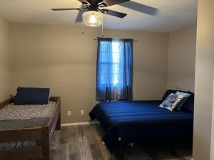 a bedroom with a blue bed and a ceiling fan at Waterfront Retreat at Rockaway with Fishing Dock home in Rockaway Beach