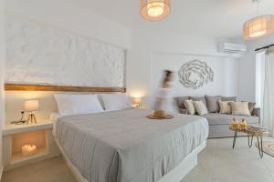 Naxos Finest Hotel & Villas في ناكسوس تشورا: غرفة نوم بيضاء مع سرير وأريكة
