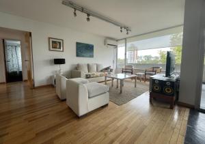 a living room with white furniture and a tv at Pichincha Guemes Balcon in Rosario