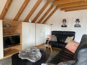 a living room with a black leather couch and a tv at Ferienwohnung Leonardo in Badem