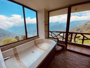 ein großes Bad mit einer Badewanne und großen Fenstern in der Unterkunft Casa de Campo El Descanso in Baños