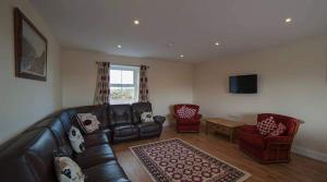 a living room with a leather couch and two chairs at Islandcorr Farm Luxury Glamping Lodges and Self Catering Cottage, Giant's Causeway in Bushmills