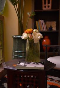 a vase of flowers on a table with a book at RIAD DAR NAOMI in Marrakesh