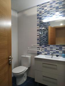 een badkamer met een toilet, een wastafel en een spiegel bij Piso familiar próximo a Santiago de Compostela y La Coruña in Ordes