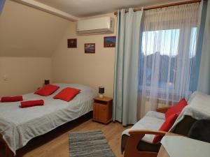 a bedroom with two beds with red pillows and a window at Magnolia Gospodarstwo Agroturystyczne in Kazimierz Dolny