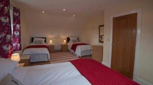 a bedroom with two beds and a red blanket at Islandcorr Farm Luxury Glamping Lodges and Self Catering Cottage, Giant's Causeway in Bushmills