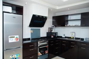 a kitchen with black cabinets and a stainless steel refrigerator at IMOLEASE HUBERT Sainte Rita in Cotonou