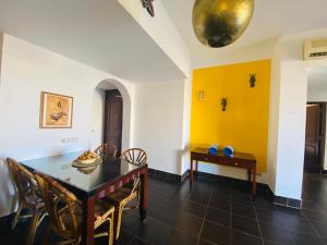 a dining room with a table and chairs and a yellow wall at Tamra Residence Apartment Families and Couples Only in Sharm El Sheikh