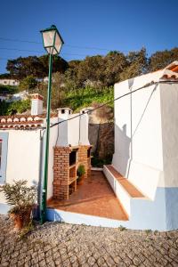 a white house with a brick fireplace and a street light at Casa Bene Holiday Home in Aljezur