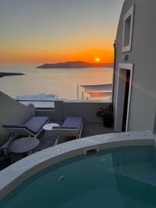 a swimming pool with a sunset in the background at Avant Garde Firostefani in Firostefani