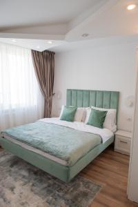 a bedroom with a large bed with a green headboard at Cosy retreat in Piatra Neamţ
