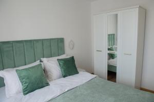 a bedroom with a bed with green and white pillows at Cosy retreat in Piatra Neamţ
