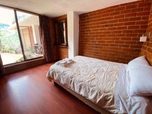 1 dormitorio con cama y pared de ladrillo en Casa de Campo El Descanso, en Baños