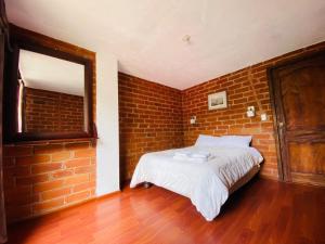 um quarto com paredes de tijolo, uma cama e um espelho. em Casa de Campo El Descanso em Baños