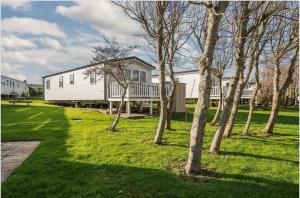 Casa blanca con porche y árboles en el césped en Water Sky Getaways 3-bedroom caravans at Durdle Door, en Wareham