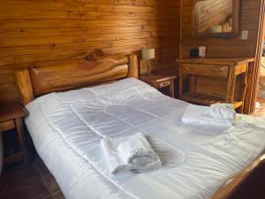 uma grande cama branca num quarto com paredes de madeira em Cabañas Ruca Carel em San Carlos de Bariloche