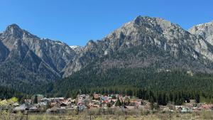 a village in front of a mountain range at Busteni Mountain View Suites by the River - EV Plug in Buşteni
