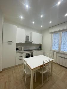 a kitchen with white cabinets and a table and chairs at LA CASETTA AL MARE in Savona