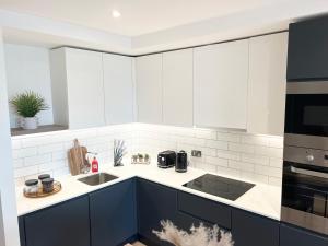 2bedroom luxury apartment city centre V في مانشستر: مطبخ فيه دواليب بيضاء وزرقاء ومغسلة
