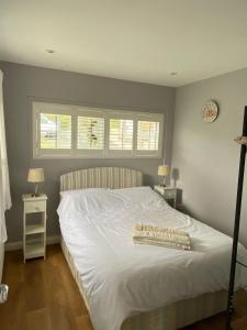 um quarto com uma cama branca e 2 janelas em Meadow cottage em Haverfordwest