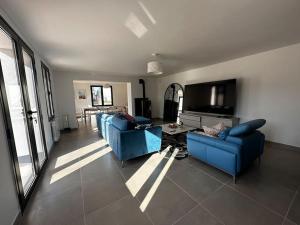 a living room with two blue couches and a tv at Maison de campagne normande in Pitres