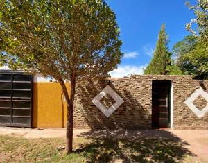 a brick building with a tree in front of it at Urqu-Pacha Alojamiento in Tinogasta