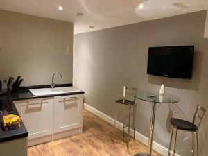 cocina con mesa y TV en la pared en Guest Suite Enfield, en Enfield