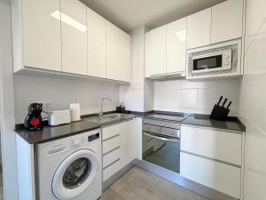 a kitchen with a washing machine and a microwave at Clauhomes Suite Center in Tarragona